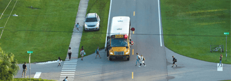 A school bus at a junction surrounded by children