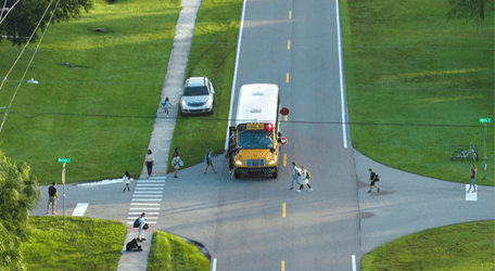A school bus at a junction surrounded by children