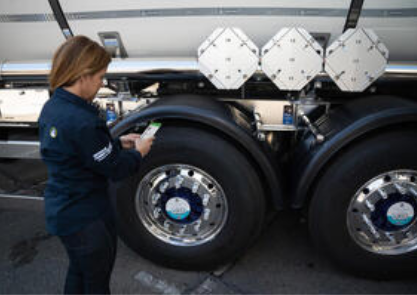 Personne devant les roues d'un camion prenant des renseignements sur son téléphone 